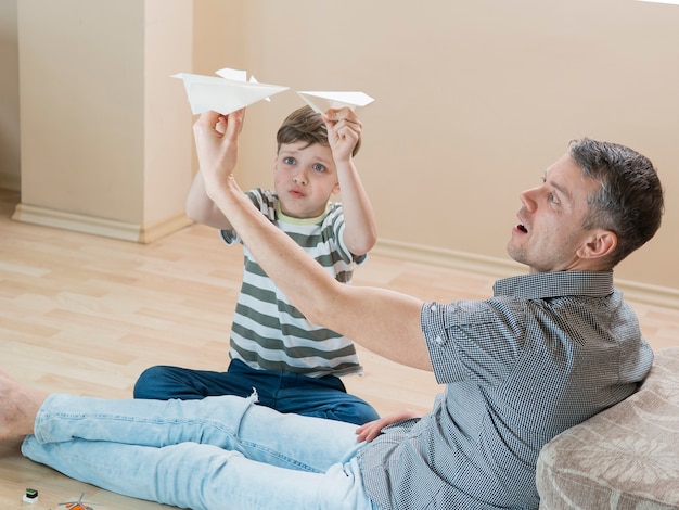 Foto gratuita padre e figlio che giocano al chiuso con aerei di carta