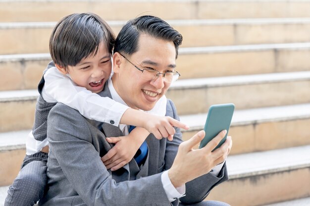 Padre e figlio che giocano insieme smart phone sul quartiere degli affari urbano