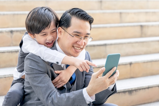 Отец и сын вместе играют в смартфон в деловом районе города