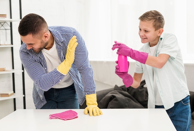 Father and son playing together while cleaning the house