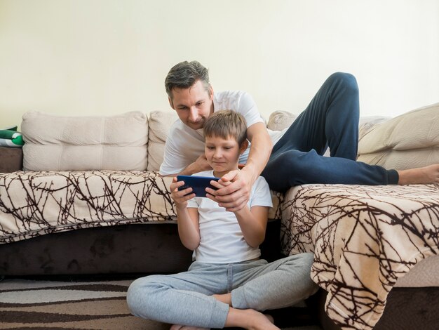 Отец и сын играют в видеоигры на мобильном телефоне