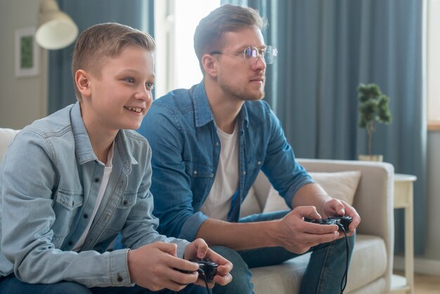 Father and son playing video games side view