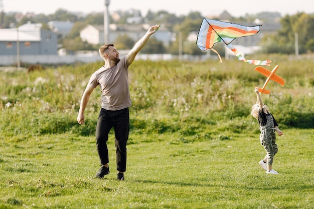  Father and son playing with a kite and having fun on summer park outdoor Curly toddler boy wearing a khaki overalls