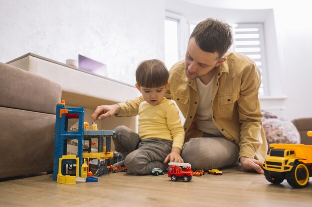 Father and son playing with trucks and lego pieces