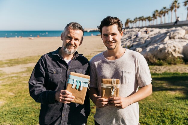 Foto gratuita padre e figlio in posa in spiaggia con presente