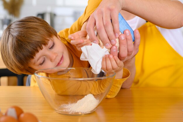 Father and son pour flour in the bowl