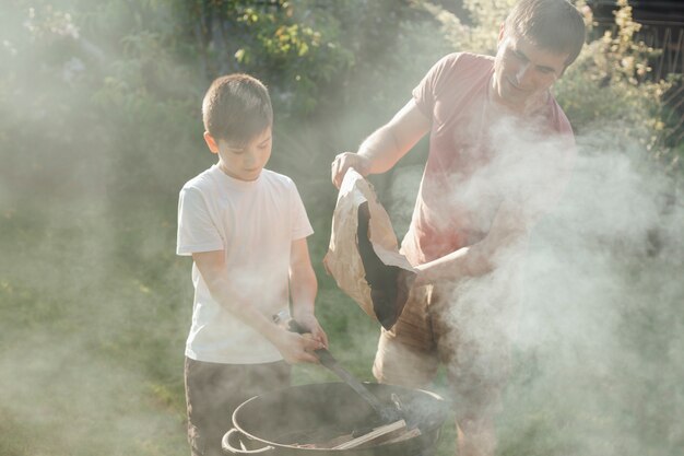 Father and son putting coal in barbecue for preparing food