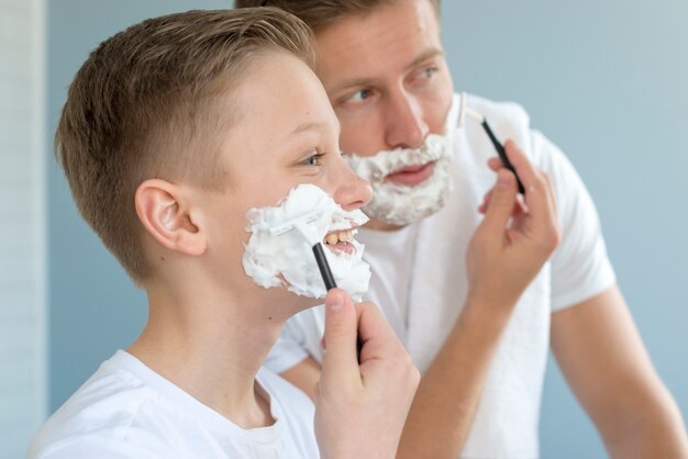 Father and son shaving in the bathroom side view