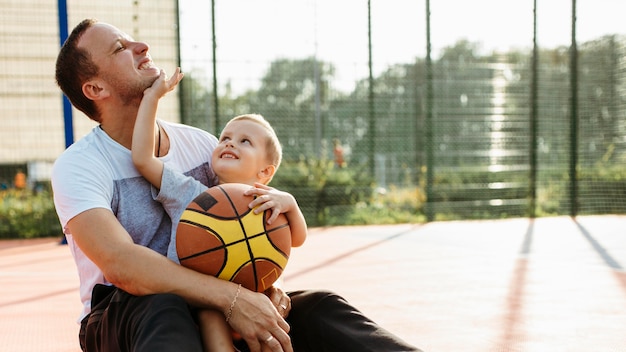 Father and son sitting on the basketball field