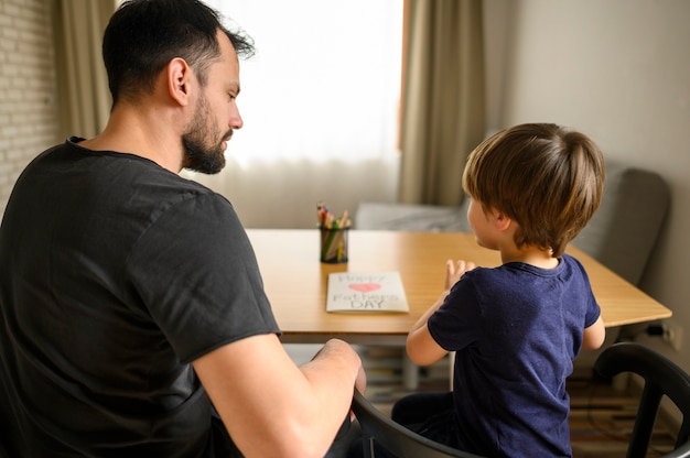 Free photo father and son sitting at table together