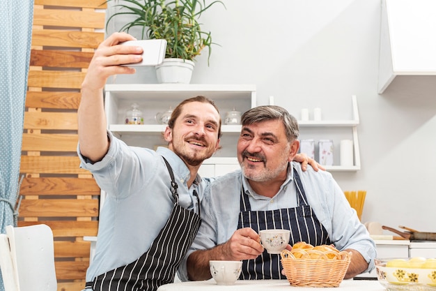 Foto gratuita padre e figlio che prendono un selfie in cucina