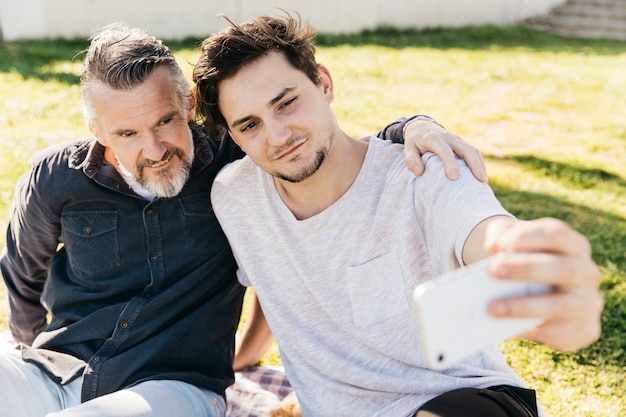 Foto gratuita padre e figlio prendendo selfie in natura