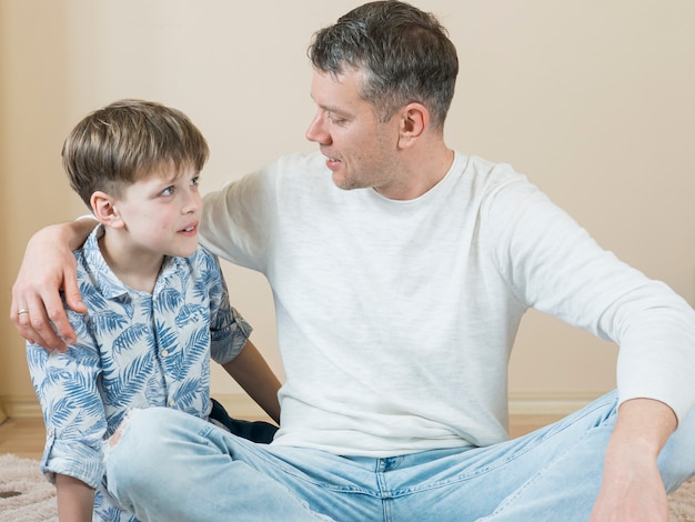 Free photo father and son talking on the floor