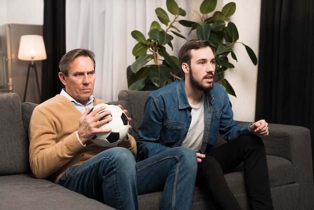 Free photo father and son watching game in living room