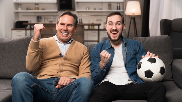 Father and son watching sports in living room