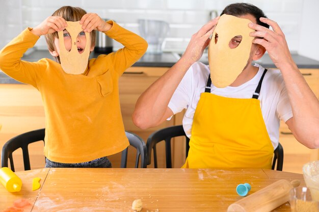 Padre e figlio che indossano maschere di pasta