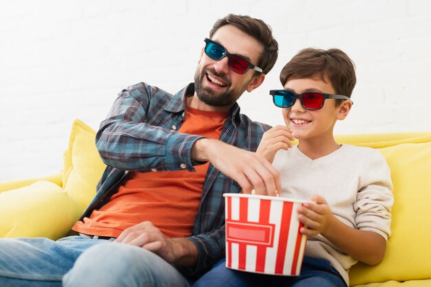 Father and soon eating popcorn and watching a movie