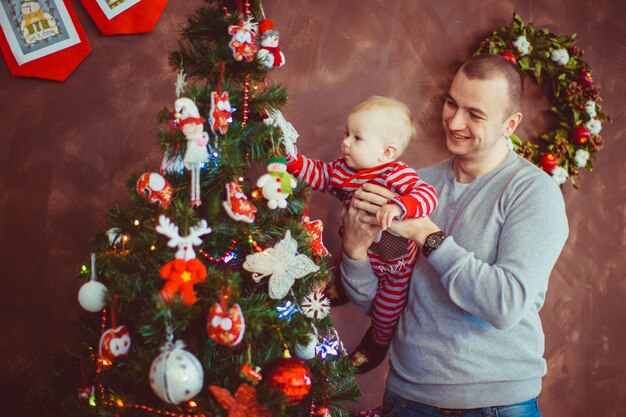 Father stands with a little son before the Christmas tree 