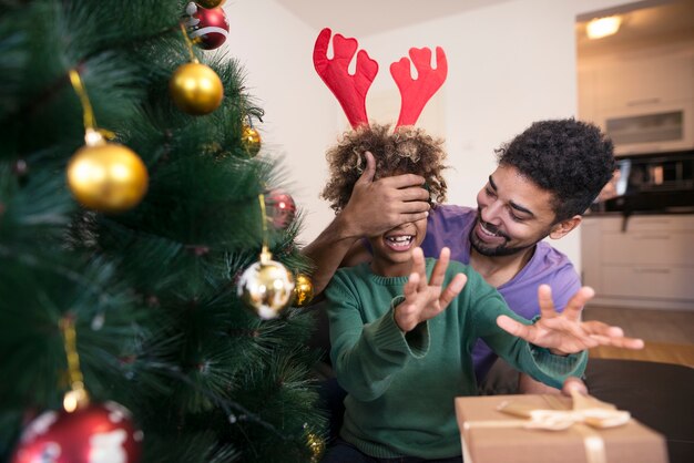 Father surprising his daughter with present by Christmas tree