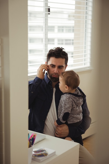 Father talking on mobile phone while holding his baby