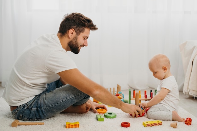 집에서 장난감을 가지고 노는 아기를 가르치는 아버지