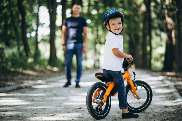 Отец учит своего маленького сына кататься на велосипеде