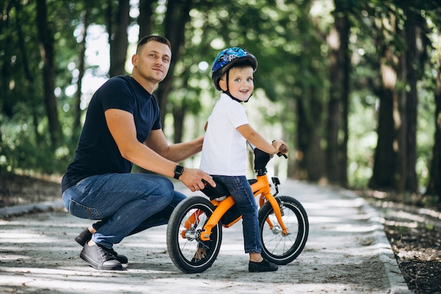 父は幼い息子に自転車に乗ることを教えています