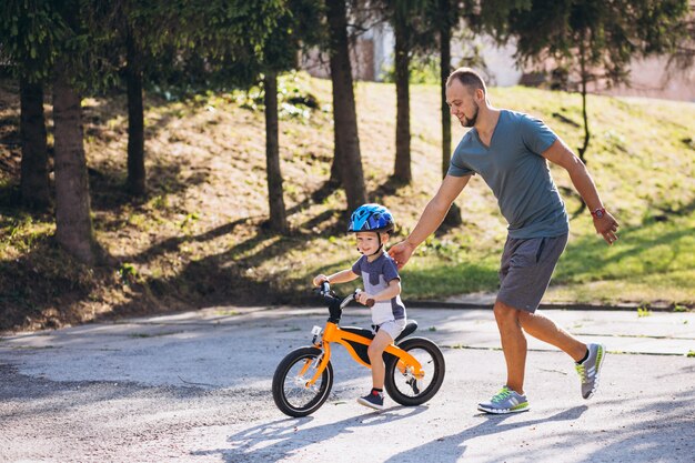 Отец учит своего маленького сына кататься на велосипеде