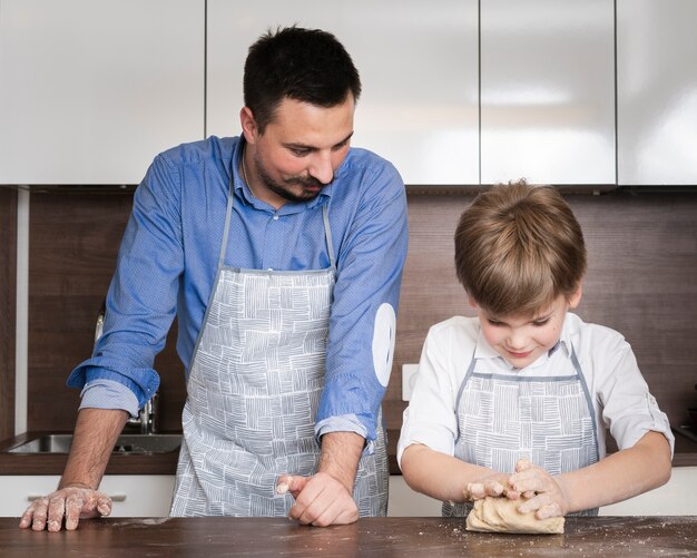 Father teaching son to roll dough