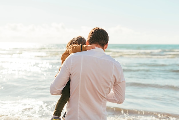 Father and toddler looking at sea waves