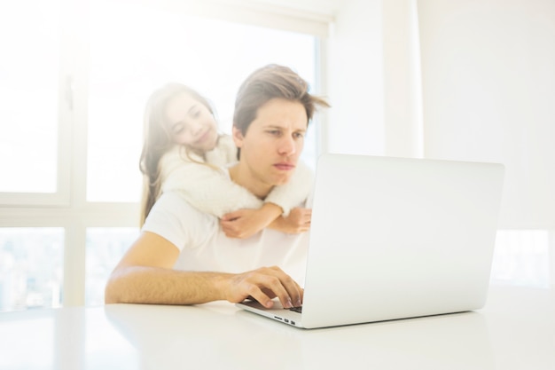 Father using laptop while daughter hugging him