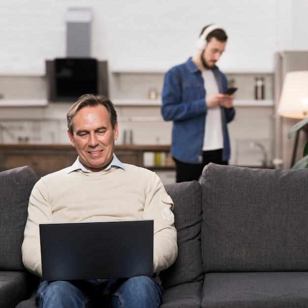 Father using laptop while son is using phone