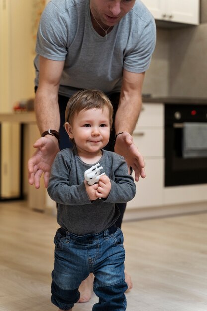 Father watching kid taking his first steps