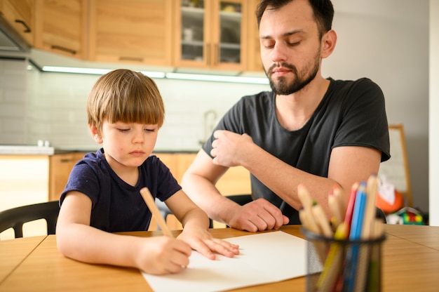 Foto gratuita padre che guarda figlio disegnare