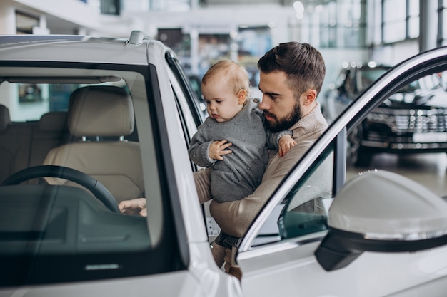 Father with baby daughter in a car showroom