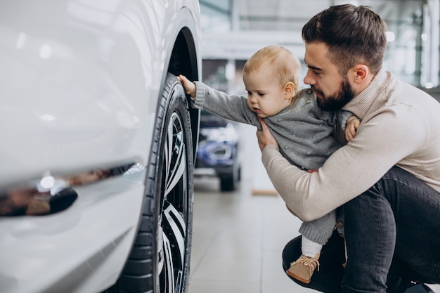 Father with baby daughter in a car showroom