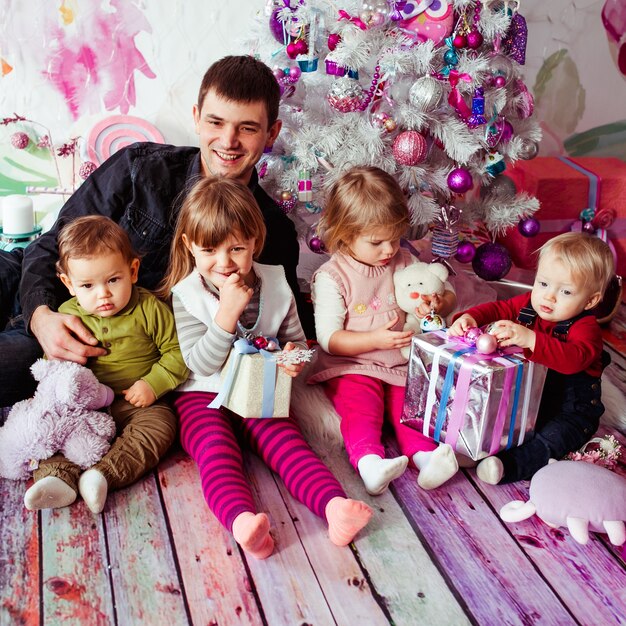クリスマスツリーの近くに座っている子供たちと父親