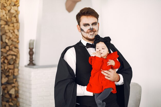 Father with daughter in costumes and makeup. Family prepare to celebration of Halloween.