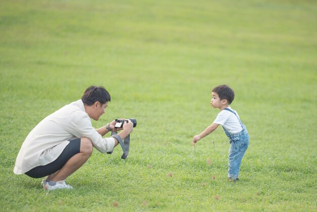 デジタル ビデオ カメラで息子を記録している父。幸せな父と息子のポートレート、公園で。