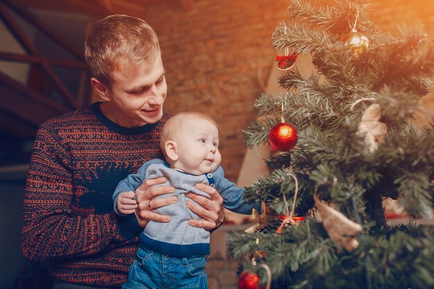 Отец со своим ребенком на руках, глядя на рождественские украшения деревьев