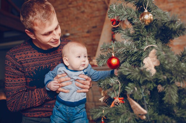 Отец со своим ребенком на руках, глядя на рождественские украшения деревьев