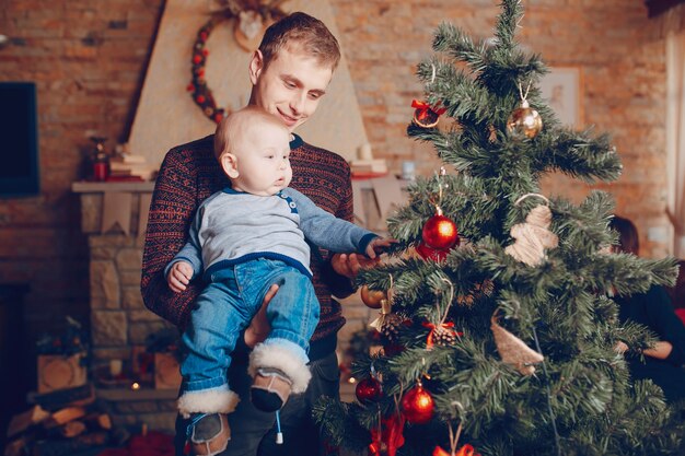 クリスマスツリーの飾りを見て腕の中で彼の赤ちゃんと父親