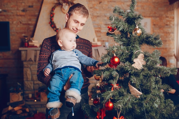 Бесплатное фото Отец со своим ребенком на руках, глядя на рождественские украшения деревьев