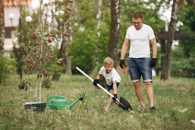 幼い息子を持つ父は庭に木を植えています