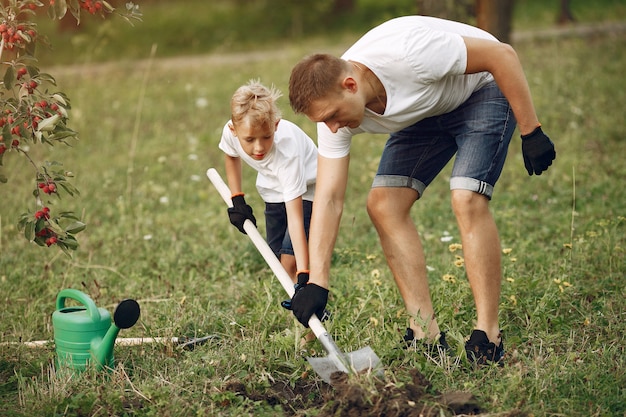 Free photo father with little son are planting a tree on a yard