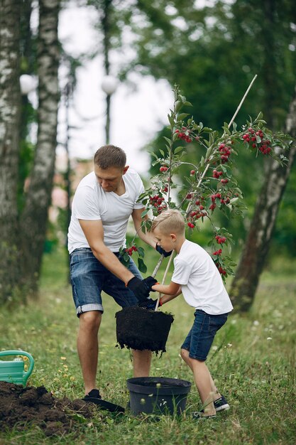 Free photo father with little son are planting a tree on a yard