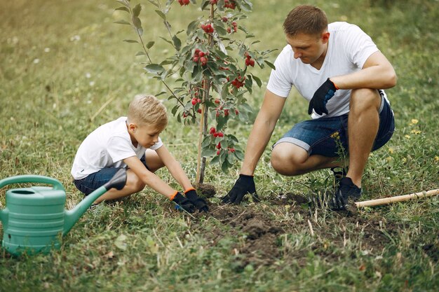 幼い息子を持つ父は庭に木を植えています