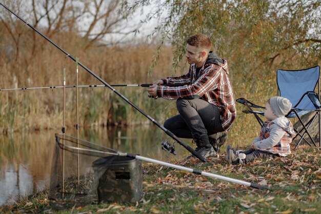 Father with little son near river in a fishing morning