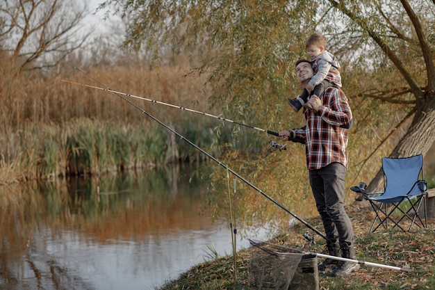 Father with little son near river in a fishing morning