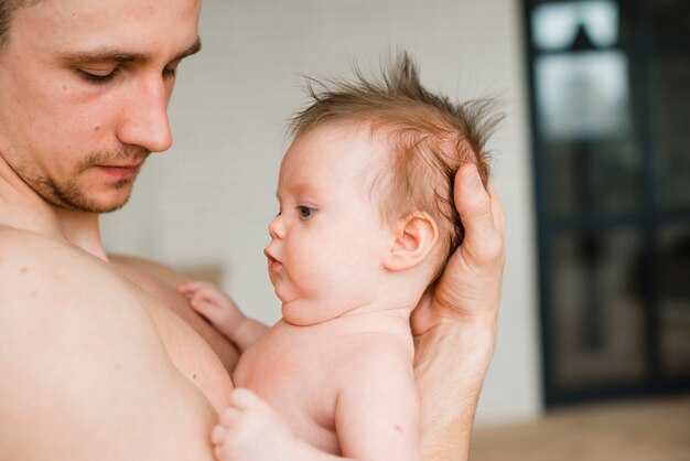 Отец с голым торсом держит ребенка